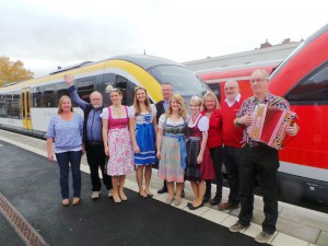 Start am Bahnhof in Wertheim für „Wein im Zug“ (von links): Sybille und Martin Ries vom Winzerkeller im Taubertal, die Külsheimer Weinprinzessin Anna Adelmann, die Taubertäler Weinkönigin Kristin Wagner, Geschäftsführer Jochen Müssig („Liebliches Taubertal“), die Dertinger Weinprinzessin Nicole Heinrich, die Külsheimer Weinkönigin Alena Wolpert, Marianne Wenzel und Hans-Otto Lausberger von der Westfrankenbahn und Musiker Gerhard Lausberger. Foto: Liebliches Taubertal