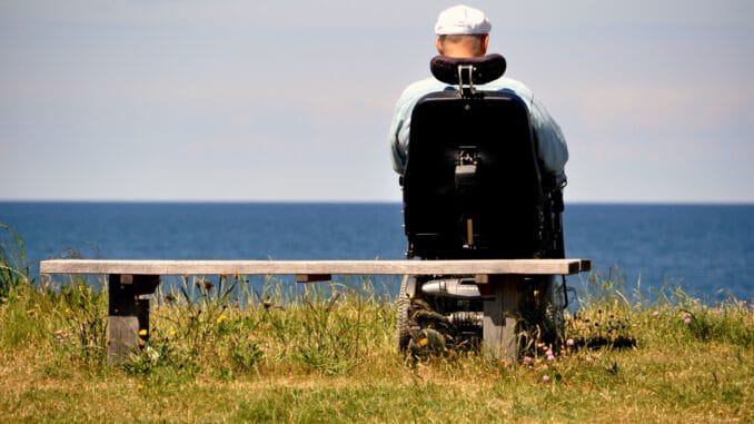 man in black jacket and white helmet standing on green grass field near body of water