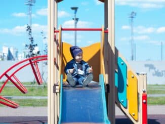 a little boy sitting on a slide at a playground