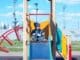 a little boy sitting on a slide at a playground