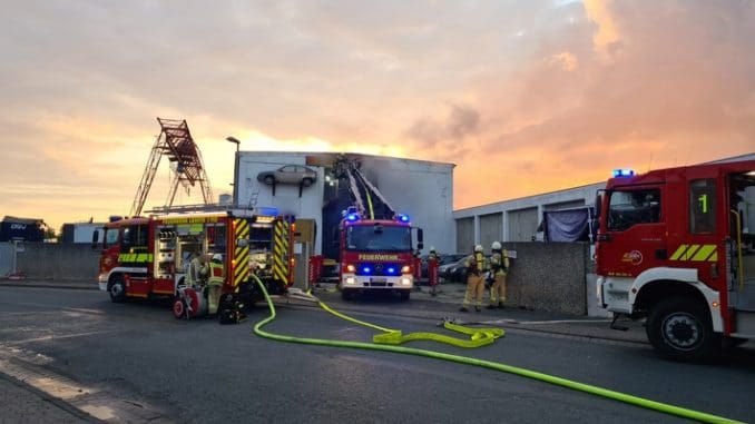 FW Lehrte: Feuer in Abschleppunternehmen: Sattelauflieger mit Elektrorollern sowie mehrere PKW brennen in Halle vollständig ab.