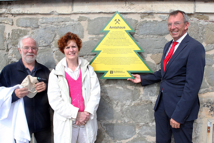 LBEG-Präsident Carsten Mühlenmeier, die Vorsitzende des Oberharzer Geschichts- und Museumsvereins (OGMV), Barbara Diedrich, und Thomas Gundermann, Beauftragter des OGMV für Dennert-Tannen (v.re.), präsentieren die neue Hinweistafel.
