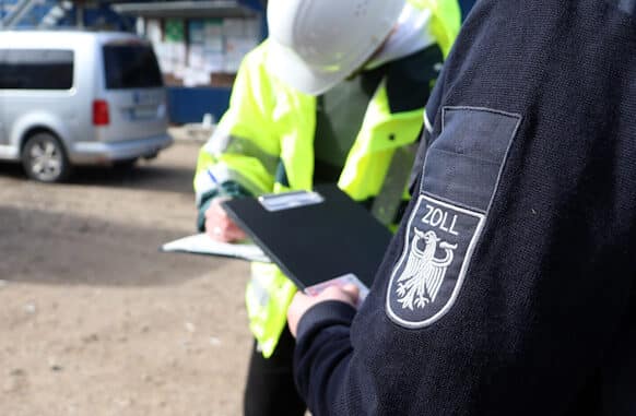 Zöllner nimmt Personalien eines Bauarbeiters auf