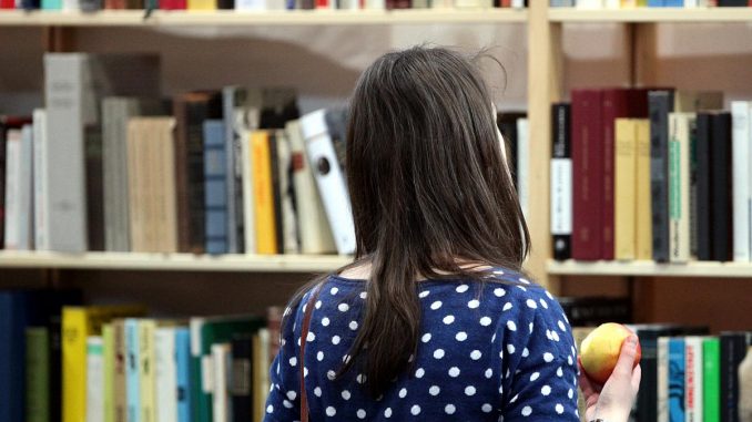 Frau steht vor einem Buchregal, über dts Nachrichtenagentur