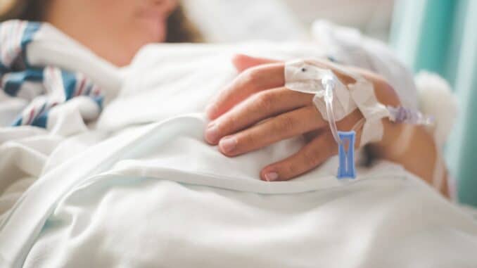 a woman laying in a hospital bed with an iv in her hand