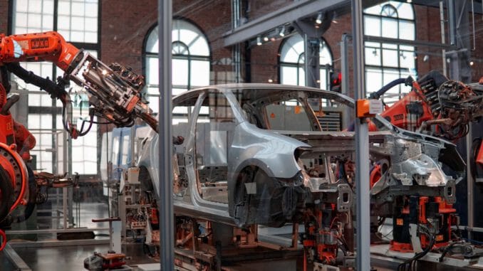 gray vehicle being fixed inside factory using robot machines