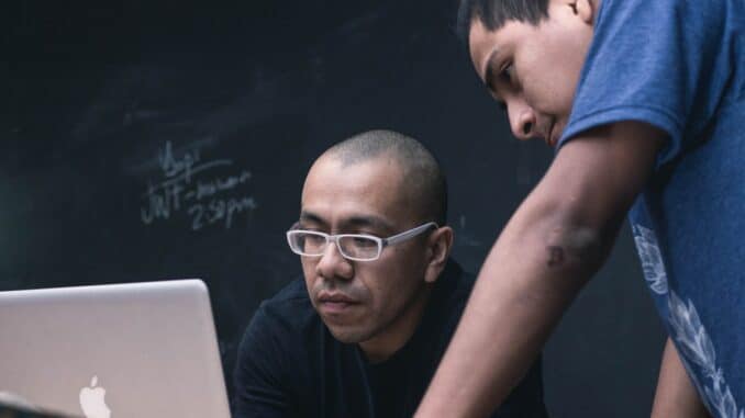 two men watching on silver MacBook